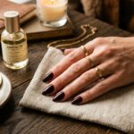 Classy cherry mocha manicure nails flat lay with espresso cup, dark wooden table, linen napkin, and gold jewelry