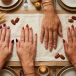 Elegant Thanksgiving nail art manicure flat lay with cozy knit sweater, wine goblet, and autumn tablescape