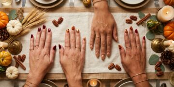 Elegant Thanksgiving nail art manicure flat lay with cozy knit sweater, wine goblet, and autumn tablescape