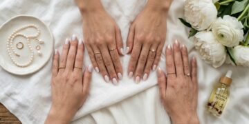 Milky white nails clean girl aesthetic manicure with gold rings, silk linen, and minimalist coffee cup flat lay