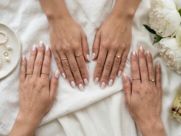 Milky white nails clean girl aesthetic manicure with gold rings, silk linen, and minimalist coffee cup flat lay