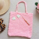 Crochet tote bag pattern in light pink yarn with scalloped shell stitch border and two straps