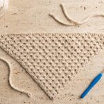 Free crochet bandana pattern hero flat-lay with cream cotton yarn skein and blue 4.0 mm crochet hook