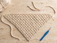 Free crochet bandana pattern hero flat-lay with cream cotton yarn skein and blue 4.0 mm crochet hook