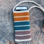 Free crochet phone pouch pattern hero flat-lay with retro striped cotton cell phone bag and crossbody strap