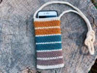 Free crochet phone pouch pattern hero flat-lay with retro striped cotton cell phone bag and crossbody strap