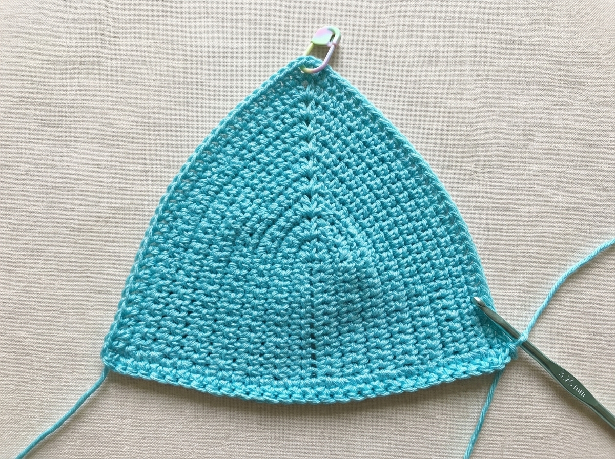 Aqua mercerized cotton triangle bikini cup in progress showing U-shaped single crochet rows and a stitch marker at the ch-1 peak