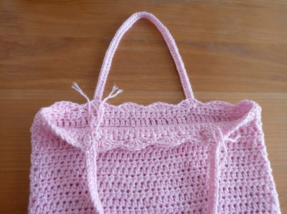 Step 5 of the crochet tote bag pattern showing the first crocheted shoulder strap attached inside the bag underneath the third shell stitch
