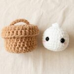 Free crochet dumpling pattern hero flat-lay with brown chenille steamer basket and white plush bao bun