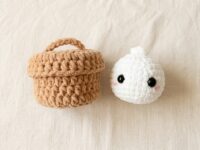 Free crochet dumpling pattern hero flat-lay with brown chenille steamer basket and white plush bao bun