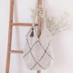 Modern cream moss stitch crochet granny square bag with charcoal whipstitch seams and tassel on natural linen