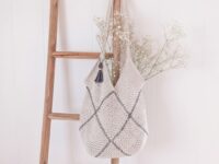Modern cream moss stitch crochet granny square bag with charcoal whipstitch seams and tassel on natural linen