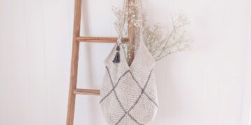 Modern cream moss stitch crochet granny square bag with charcoal whipstitch seams and tassel on natural linen