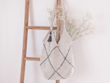 Modern cream moss stitch crochet granny square bag with charcoal whipstitch seams and tassel on natural linen